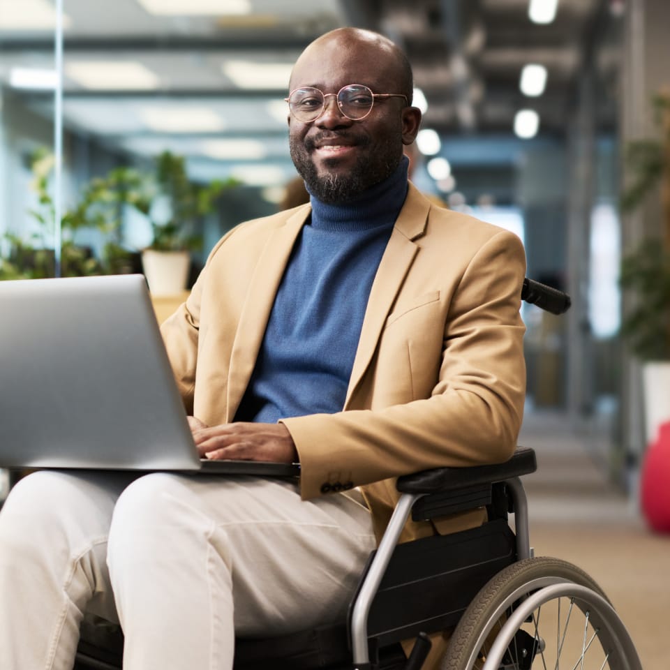 Business man using laptop in wheelchair friendly office