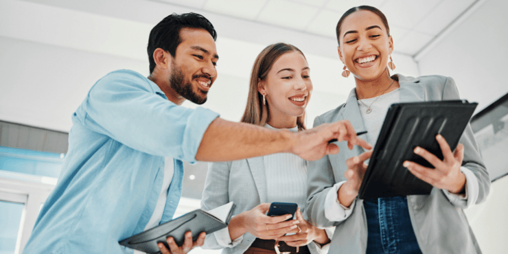 A group of three business people looking at a tablet together. 