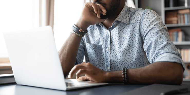 A man sitting at a desk and doing work on his laptop. 