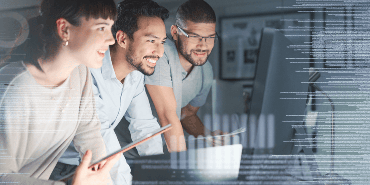 Three professionals standing around a desktop computer. 